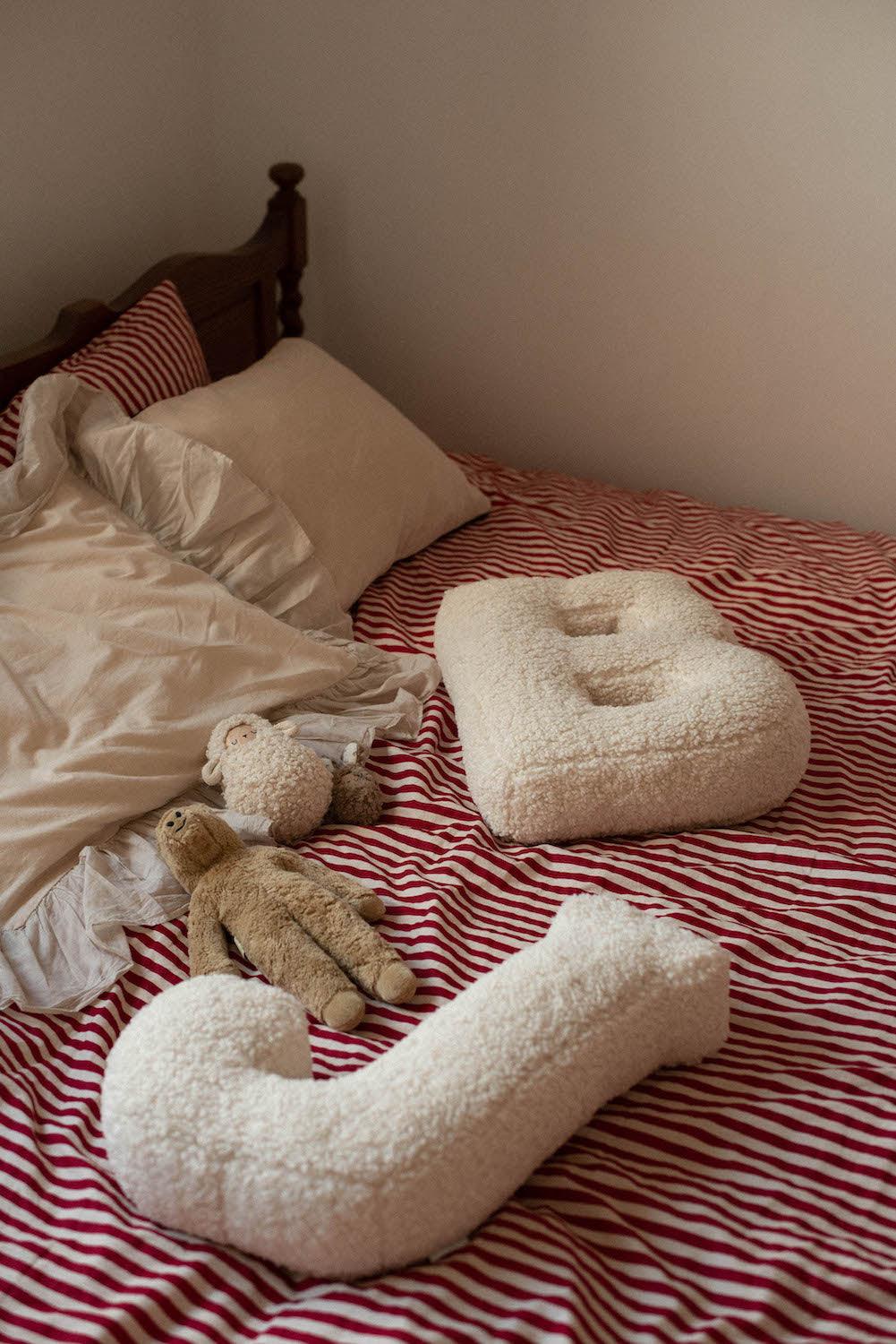 Boucle Letter cushion B and J by Bettys Home Teddy Letter Pillow lying on bed in bedroom as bedroom decorations 