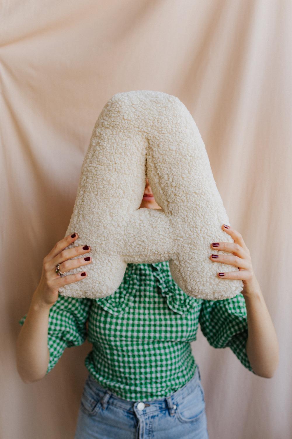 Boucle Letter cushion A by Bettys Home Teddy Letter Pillow held by woman in green shirt in front of her 