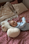baby lying on boucle pillow on bed kids room deco idea
