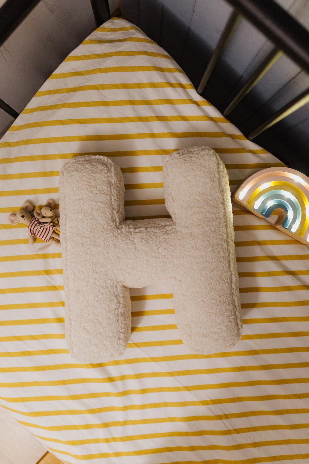 boucle letter cushion H teddy pillow by bettys home lying in kids crib with maileg mouse and rainbow lamp